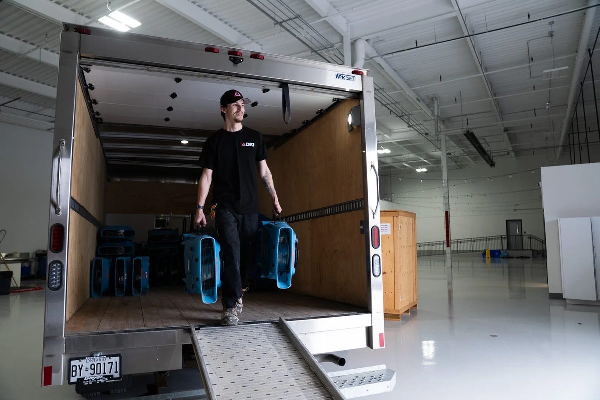 DKI technician unloading air movers from a truck for structural drying